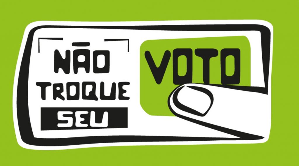 Sobre fundo verde musgo, ilustração com dedo sobre a palavra Voto como se estivesse apertando um botão. A palavra compõe a frase Não troque seu voto.