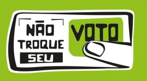 Sobre fundo verde musgo, ilustração com dedo sobre a palavra "Voto" como se estivesse apertando um botão. A palavra compõe a frase "Não troque seu voto".