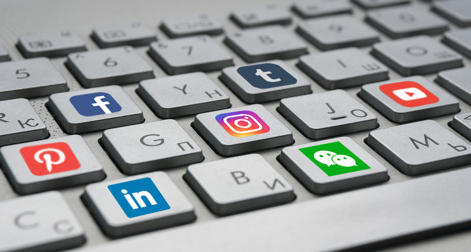 Teclado de computador na cor cinza com desenhos das logomarcas de algumas redes sociais nas teclas (Instagram, facebook, twitter etc)