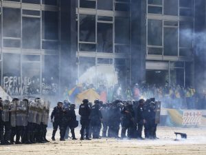 Em meio a muita fumaça, grupo de policiais com escudos avança para expulsar golpistas diante do Palácio do Planalto