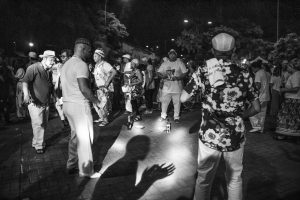 Foto em preto e branco de roda de homens e mulheres dançando