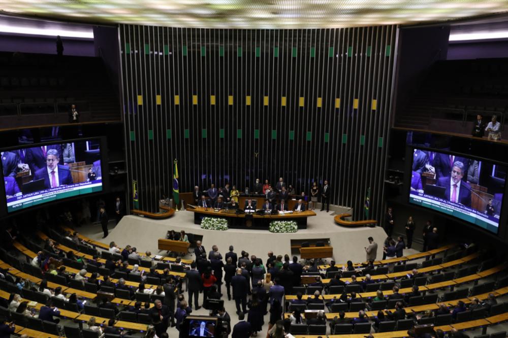 Foto do plenário da Câmara dos Deputados, onde se vê a mesa diretora, dezenas de pessoas em pé no centro do plenário e várias outras sentadas nas bancadas.