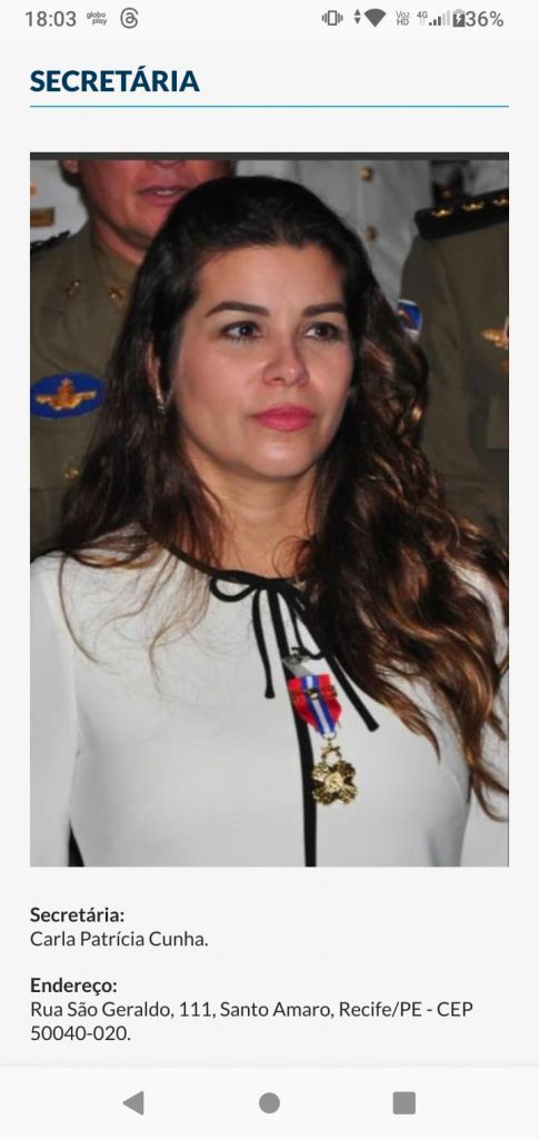 Foto de Carla Patrícia Cunha, ex-secretária de segurança de Pernambuco. Ela é uma mulher branca, que usa blusa branca, de cabelos castanhos compridos, com laços de detalhes pretos, fotografada do abdômen para cima.