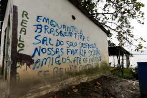 parede de casa abandonada pichada em azul com a frase "Enquanto a Braskem tira o sal do solo destrói nossas famílias"
