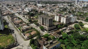 Foto aérea do bairro do Pinheiro, onde se vê prédios de poucos andares e centenas de casas com sinais de abandono em ruas vazias.