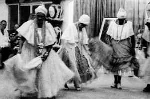 Foto em preto e branco de filhas de santo do candomblé, dançando em trajes rituais