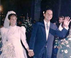 Foto colorida do casamento de Renata Campos e Eduardo Campos. Ela está à esquerda, muher branca, de cabelos pretos, usando vestido de noiva com grinalda na cabeça. À direita, de mãos dadas com ela, ele Eduardo usa paletó azul escuro, camisa branca e gravata listrada.