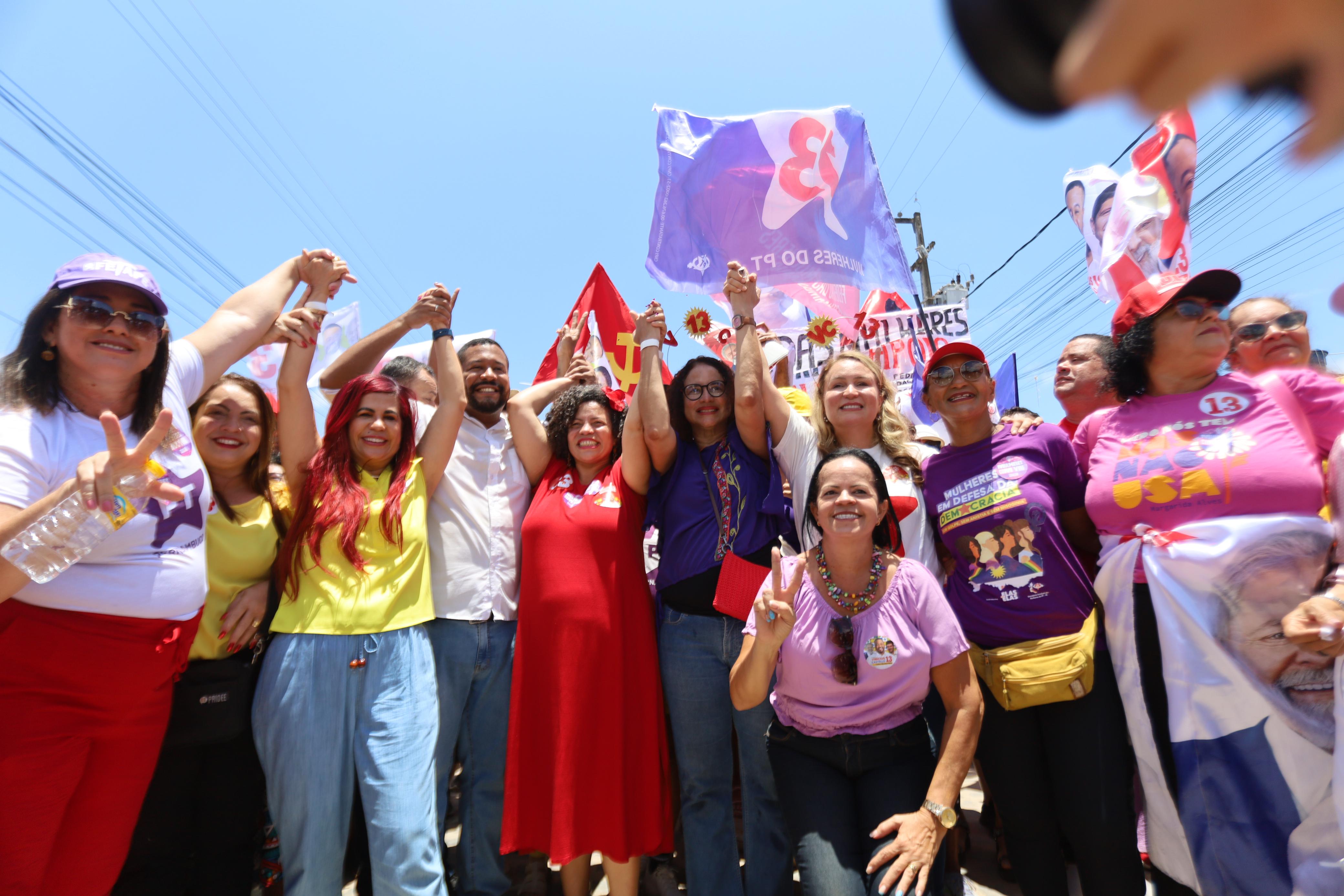 Foto colorida com o candidato de Olinda Vinicius Castello de mãos dadas e levantadas com várias mulheres durante caminhada em apoio ao petista