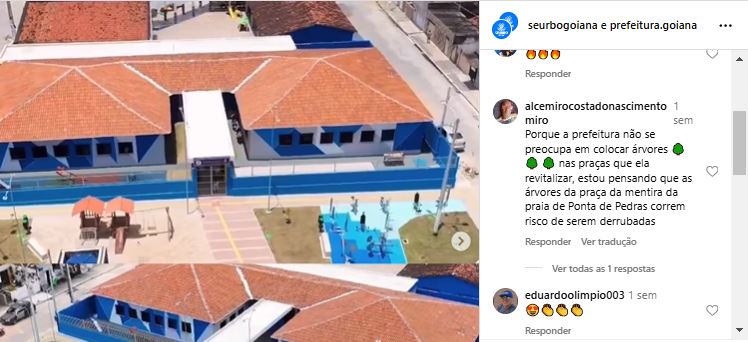 Publicação do instagram com imagem aérea de um espaço revitalizado, com edifícios de telhado laranja e áreas azuis. Há mesas de concreto, uma pequena praça e brinquedos infantis em um parque. Comentários: Usuário: alcemirocostadonascimento Texto: Por que a prefeitura não se preocupou em colocar árvores 🌳 nas praças que revitaliza, estou pensando que as árvores da praça da mentira da praia de Ponta da Pedras correm risco de serem derrubadas.