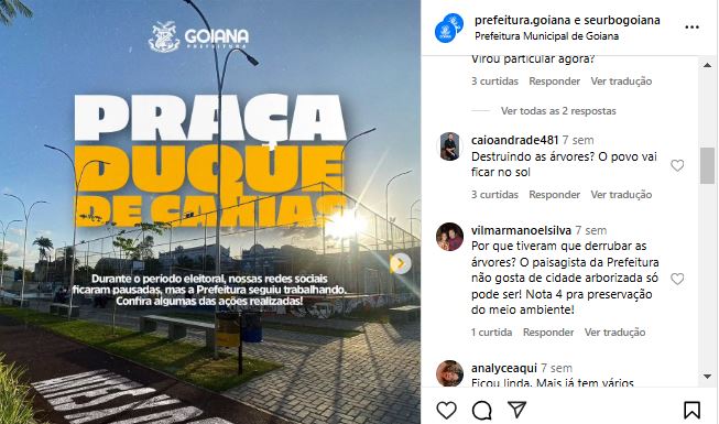 Publicação do instagram com imagem de uma praça iluminada pelo sol ao fundo, com algumas árvores ao redor, gramado bem cuidado e um caminho pavimentado. O letreiro exibe Praça Duque de Caxias, e há o logotipo da Prefeitura de Goiânia no canto superior esquerdo. Texto sobre a imagem: Durante o período noturno, além das redes sociais reconectarem pessoas, as praças reúnem segurança, bem-estar e tranquilidade. Comentários: Usuário: caioandrade481 Texto: Destruiu as árvores? O povo vai ficar no sol! Usuário: vilmarmanoelsilva Texto: Por que tiveram que derrubar as árvores? O responsável da Prefeitura não gosta de cidade arborizada não? Árvores são fundamentais para quem quer preservar o meio ambiente.