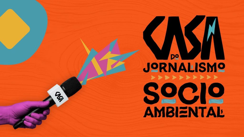Sobre fundo na cor laranja, à esquerda um microfone preto é empunhado por uma mão colorida de roxo. Do microfone, saem grafismos nas cores roxa, azul e amarela.À direita, em letras pretas numa fonte que remete a algo manuscrito pintado sobre uma superfície, há a inscrição Casa do Jornalismo Socio Ambiental, com grafismos amarelos e azuis entre as letras e entre as linhas.