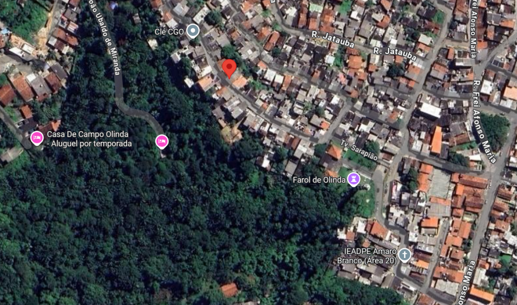 A imagem mostra uma vista aérea de um bairro residencial em Olinda, Pernambuco. As casas estão dispostas de forma compacta, com telhados próximos uns dos outros e ruas estreitas entre elas. Algumas das vias identificadas são a Rua Jataúba, Travessa Sarapião, Rua Frei Afonso Maria e Rua João Ubaldo de Miranda. Há pontos de referência marcados, como a “Casa de Campo Olinda – Aluguel por temporada”, o “Farol de Olinda”, o local chamado “Clê CGO” e a igreja “IEADPE Amaro Branco (Área 20)”. A vegetação é escassa, predominando construções urbanas.