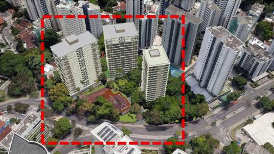 A imagem mostra uma vista aérea de uma área urbana com vários prédios altos. No centro, há três edifícios residenciais destacados por uma linha vermelha tracejada, indicando uma região específica. Dentro desse perímetro, nota-se áreas verdes com árvores e uma construção menor, possivelmente uma casa ou edifício de poucos andares. Ao redor, há ruas e outros prédios altos, compondo um cenário típico de bairro verticalizado.