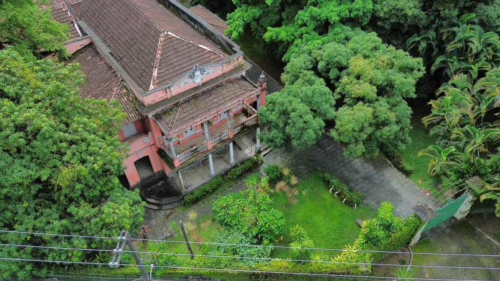 Vista aérea da Mansão Harley Lundgren cercada de árvores na Rua Padre Roma, entre prédios da Zona Norte do Recife