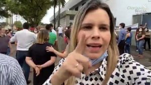 Grupo de pessoas reunidas ao ar livre; em destaque, uma mulher aponta para a câmera com máscara no queixo. Ao fundo, aparece o nome “Clarissa Tércio” junto da frase “em defesa da família”.